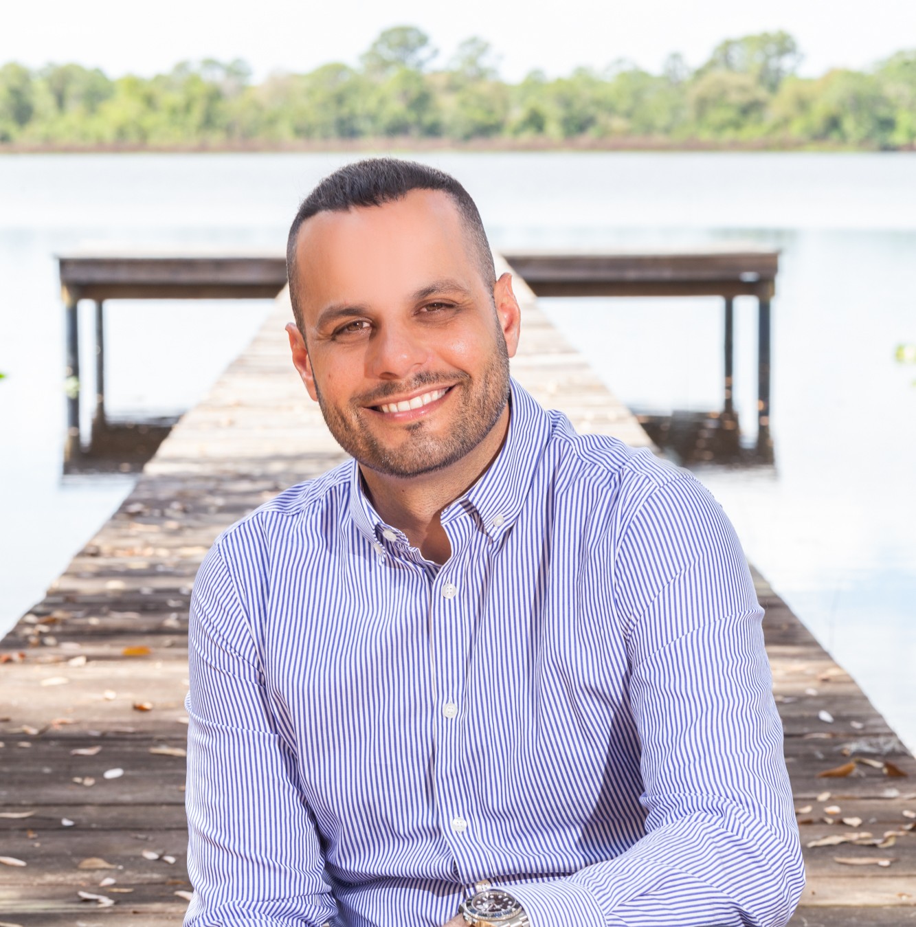 Lazaro Martinez, broker at Hammock Realty, on a wooden dock over a lake